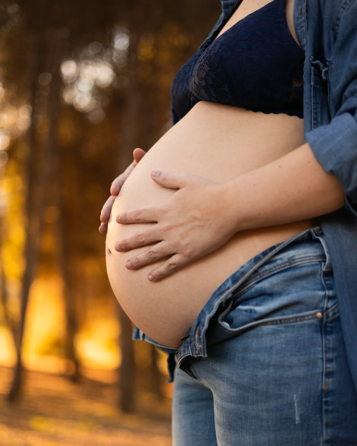 Sesión de embarazo — manos formando un corazón sobre la barriga